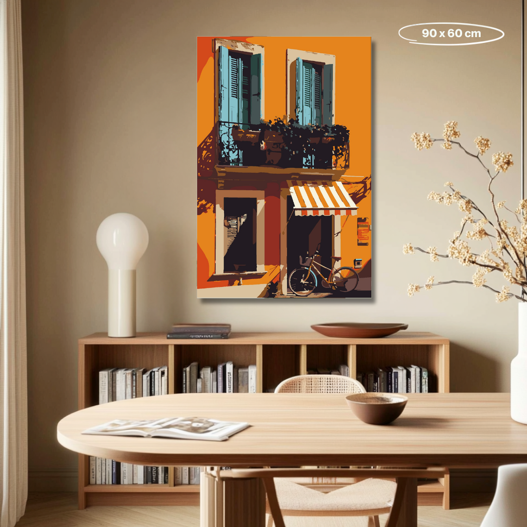 Malen-nach-Zahlen-Set 'Terracotta Balcony' mit mediterranem Stadtmotiv. Das Bild zeigt eine orangefarbene Fassade mit zwei blauen Fensterläden, einem Balkon mit Pflanzen und einer gestreiften Markise über einer Eingangstür. Ein Fahrrad lehnt an der Wand, während das Sonnenlicht warme Schatten wirft.